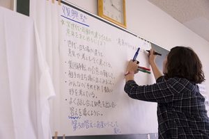 写真：支援活動のリストをホワイトボードに書く女性