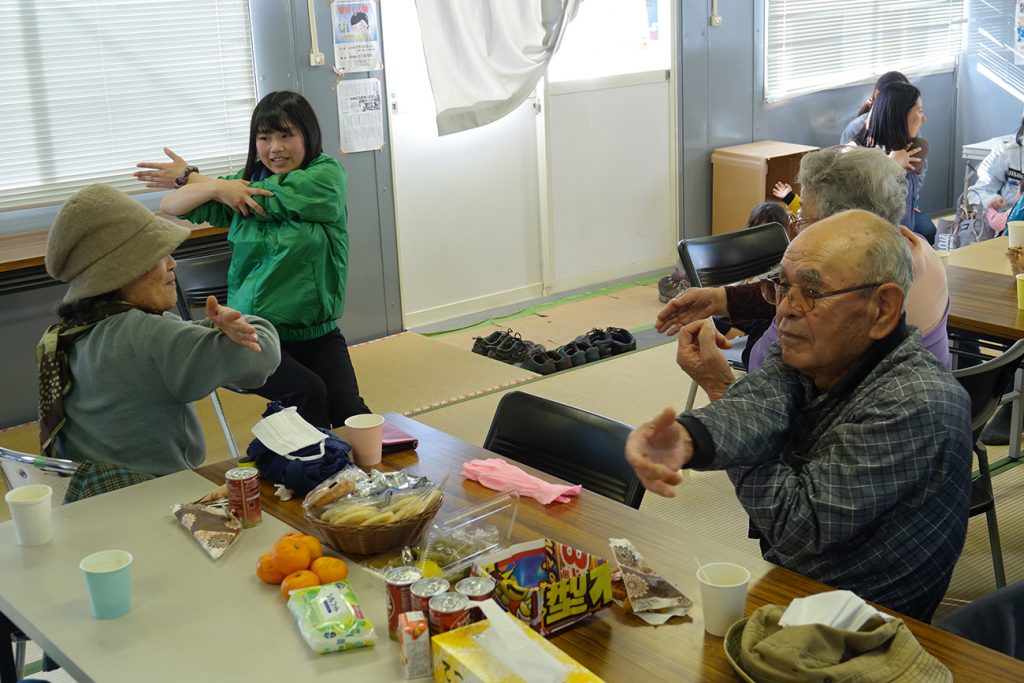 写真：プレハブ小屋にあつまった参加者たちがストレッチしている様子