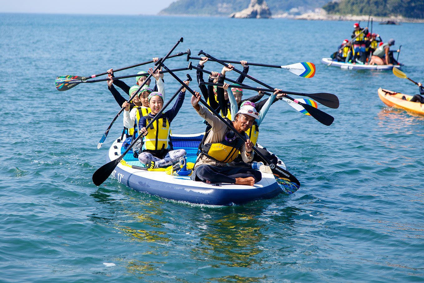 写真：海ごみ拾いイベントで回収された沢山のごみと、イベント参加者たちの集合写真。