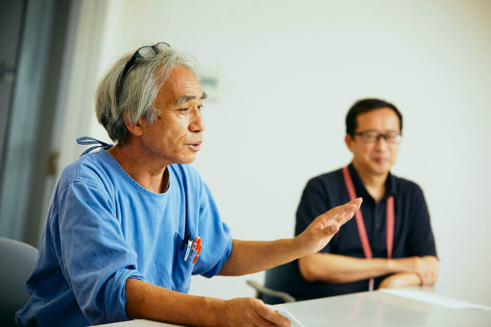 写真:取材に答える臼井さんと、その奥に座る中野さん