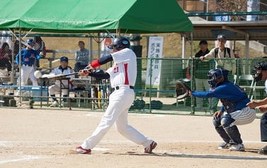 写真:ボールを打つバッター、かまえるキャッチー