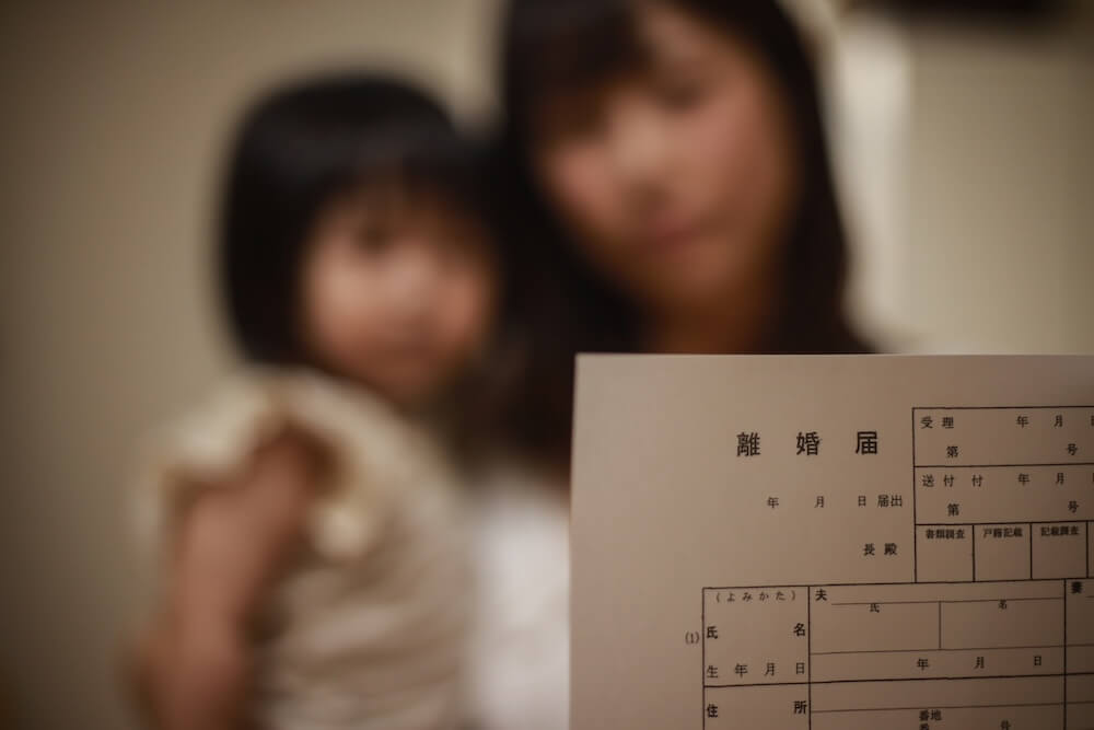 イメージ：離婚届を持つ、幼い子どもを抱えた女性