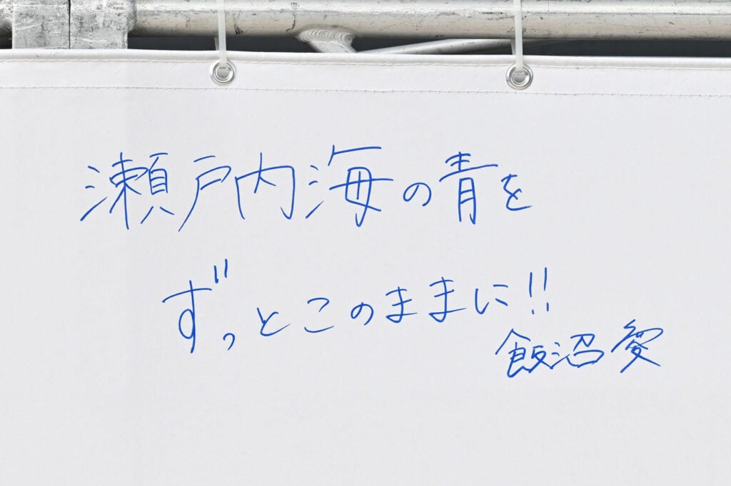 写真：メッセージフラッグに書かれた飯沼さん自筆のメッセージ「瀬戸内海の青をずっとこのままに‼ 飯沼愛」