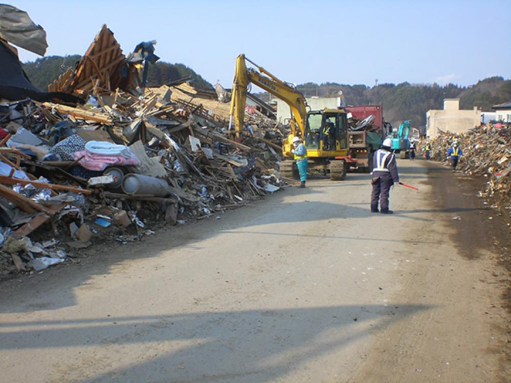 東日本大震災の際の道路啓開の様子。重機を使って道路をふさいでいたがれきを、道路脇に積み上げている