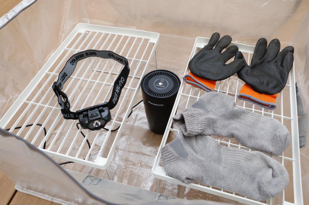 「なんでもバッグ」を開くと、中の棚にはにおいが気になりやすい物が置かれている。写真では例として、ヘッドライト、ゴム手袋、靴下が並べられている。