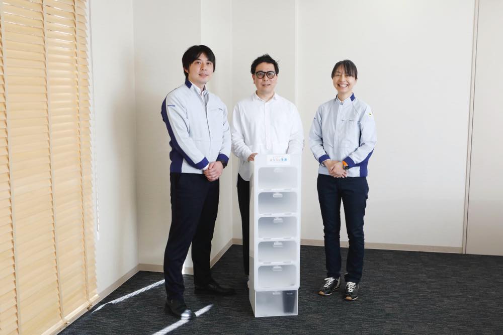 部屋の一角で、大江さん、渡辺さん、中川さんが横に並び、その前には白いシューズボックスが置かれている。