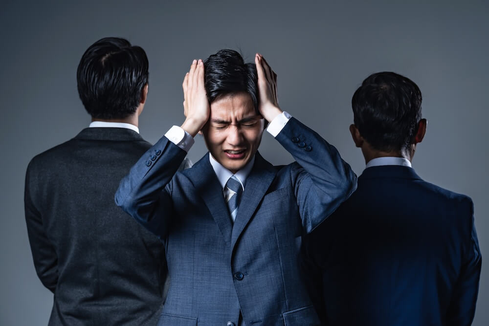 イメージ：部下に間を挟まれ、頭を抱える上司