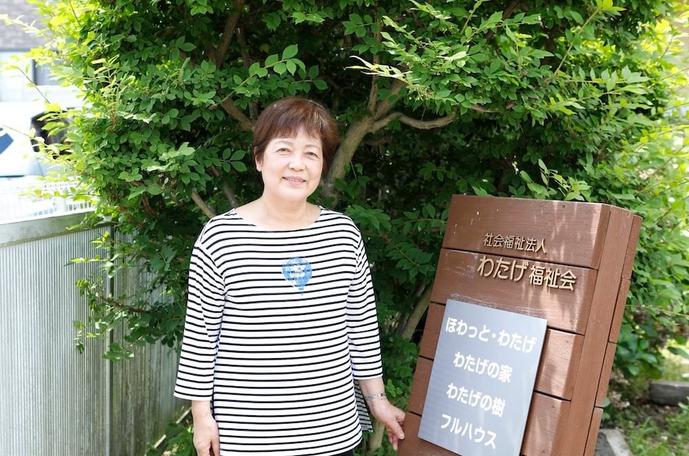 わたげの会の施設の前で笑顔を向ける秋田さん