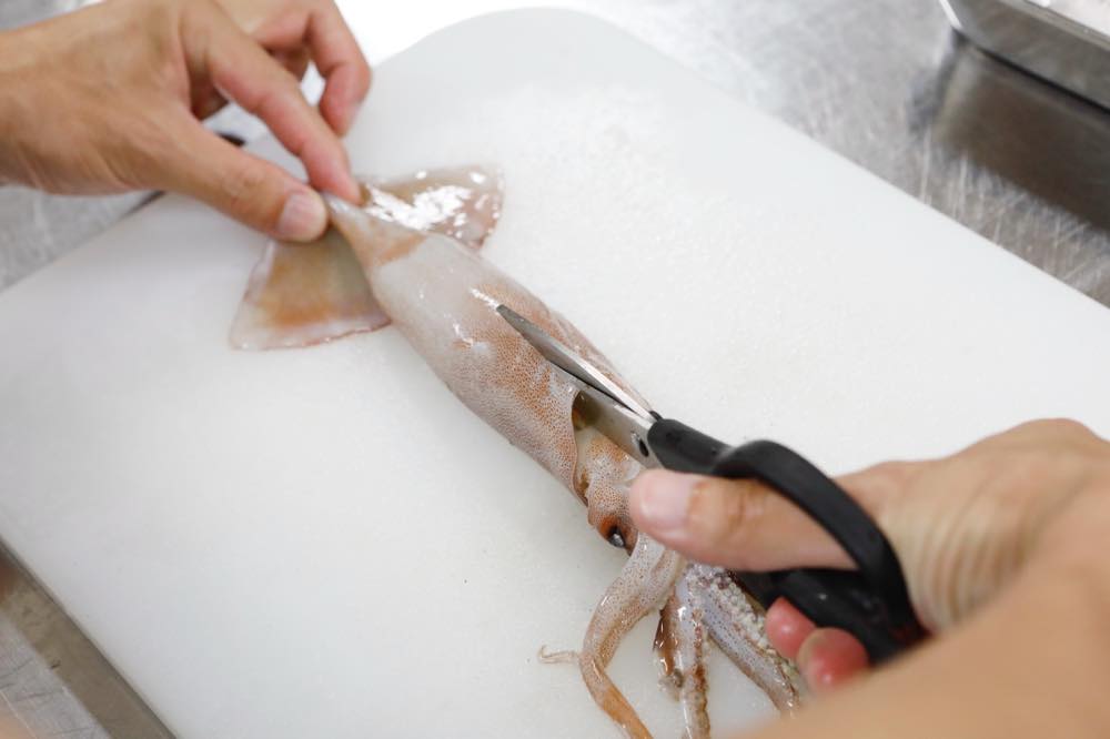 イカの胴体にはさみを入れている様子