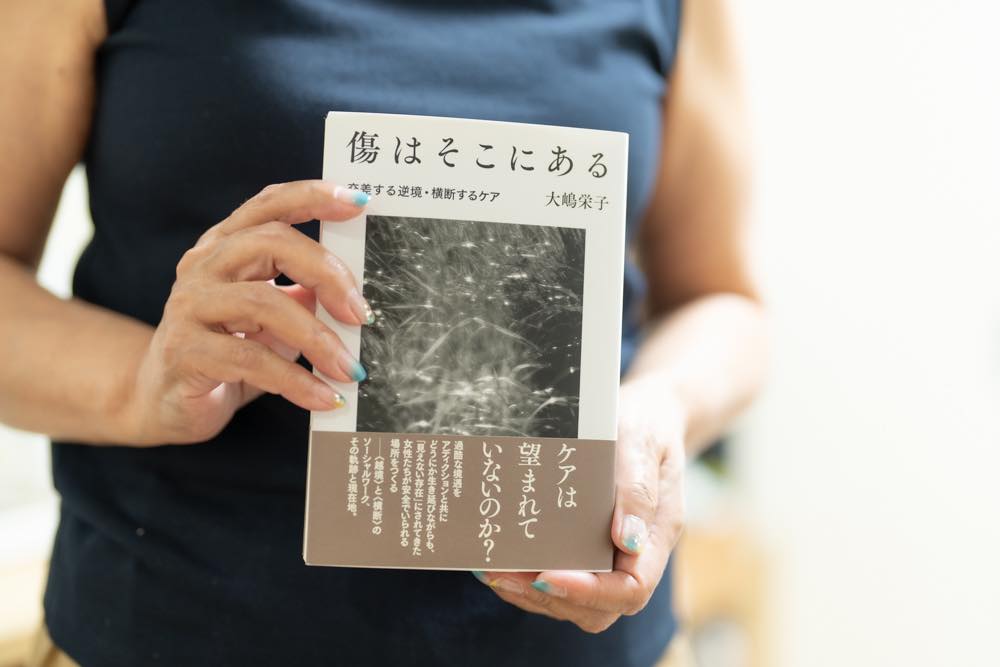 自著「傷はそこにある」を手に持つ大嶋さん